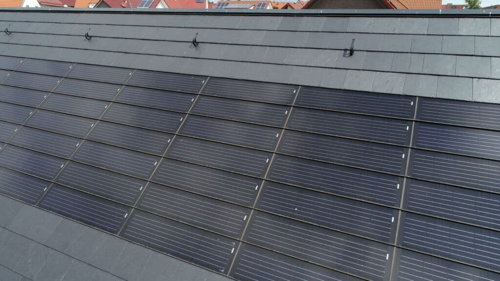 Detailaufnahme eines Schieferdachs mit bündig integrierten Solarmodulen – ästhetische und effiziente Energielösung für geneigte Dächer.