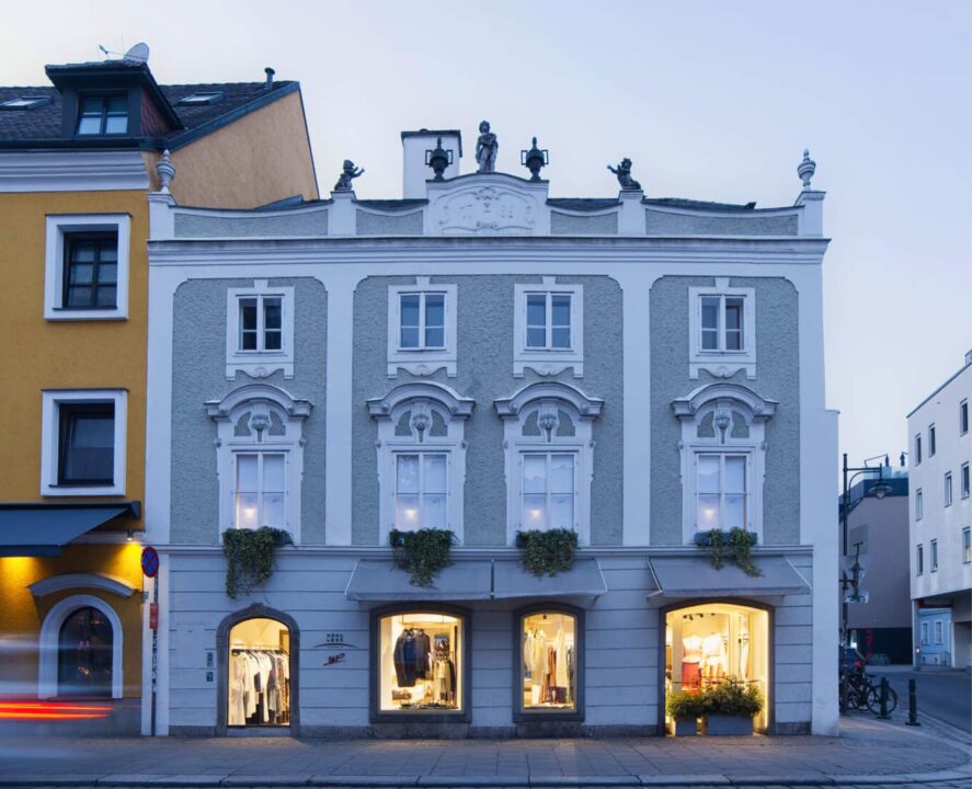 Restaurierte historische Straßenfassade mit Schaufenstern und denkmalgeschütztem Barockgiebel.