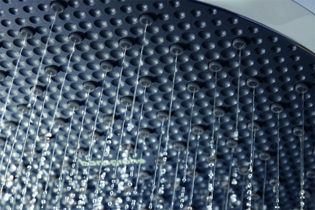 Detailansicht einer Hansgrohe Kopfbrause mit vielen feinen Wasserstrahlen, Strahldüsen aus schwarzem Kunststoff klar erkennbar.