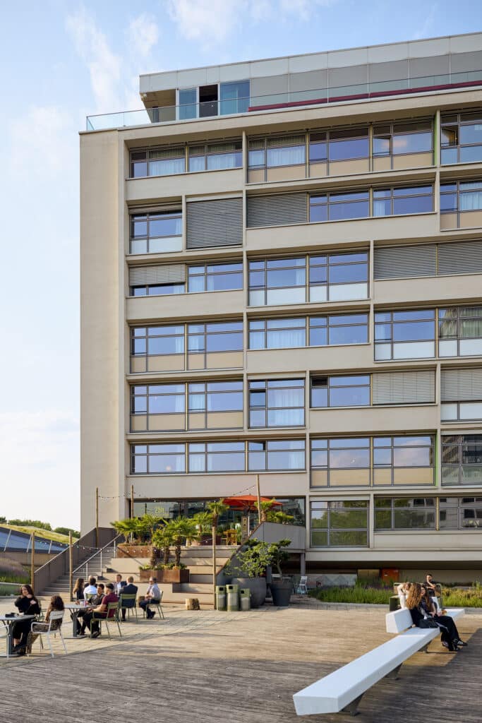 Fassade des 25hours Hotels Bikini Berlin mit Terrasse, Gästen und urbanem Flair bei Tageslicht