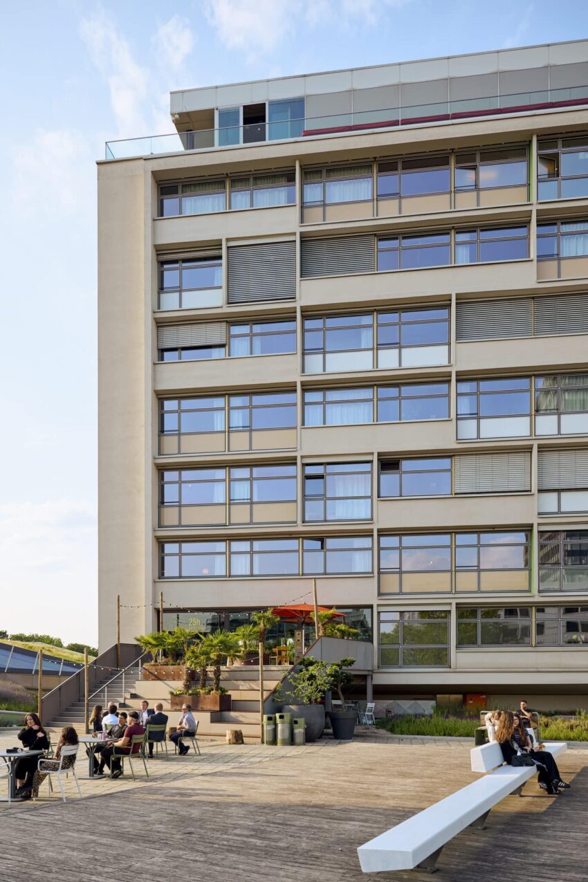 Fassade des 25hours Hotels Bikini Berlin mit Terrasse, Gästen und urbanem Flair bei Tageslicht