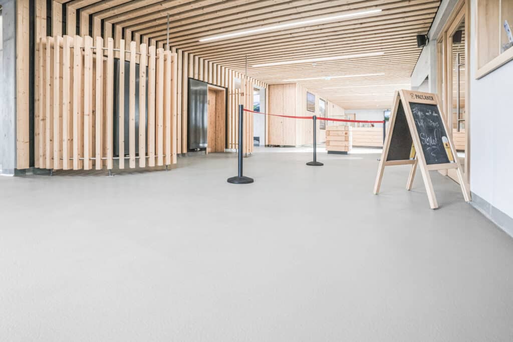 Sanierter Eingangsbereich der Tegelbergbahn in Schwangau mit hellem OS11a-Boden, Holzlamellen und moderner Empfangssituation.