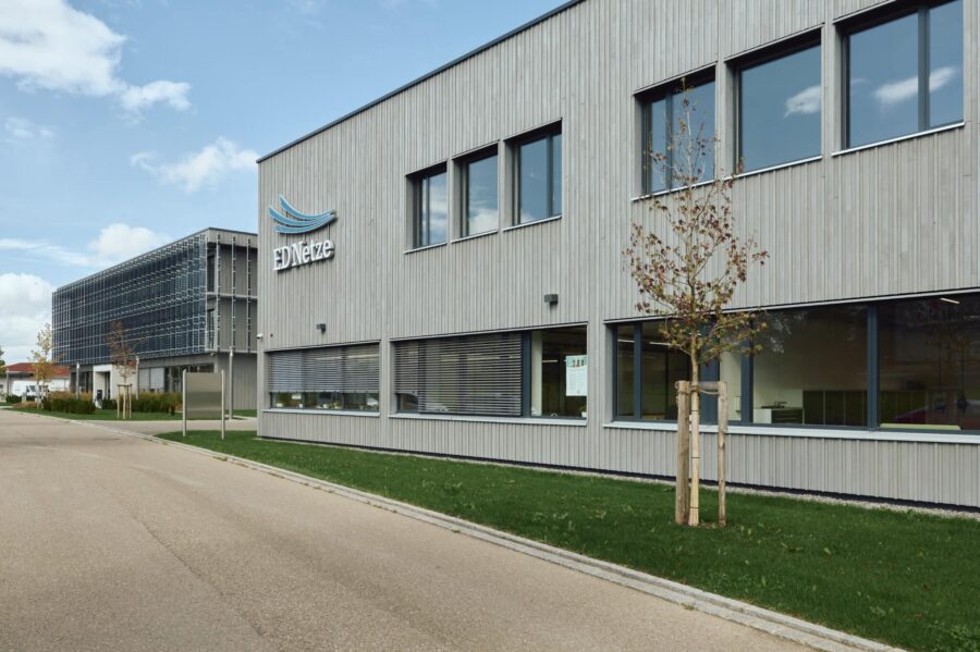 Außenansicht eines modernen Bürogebäudes mit Holzfassade und ED Netze Logo.