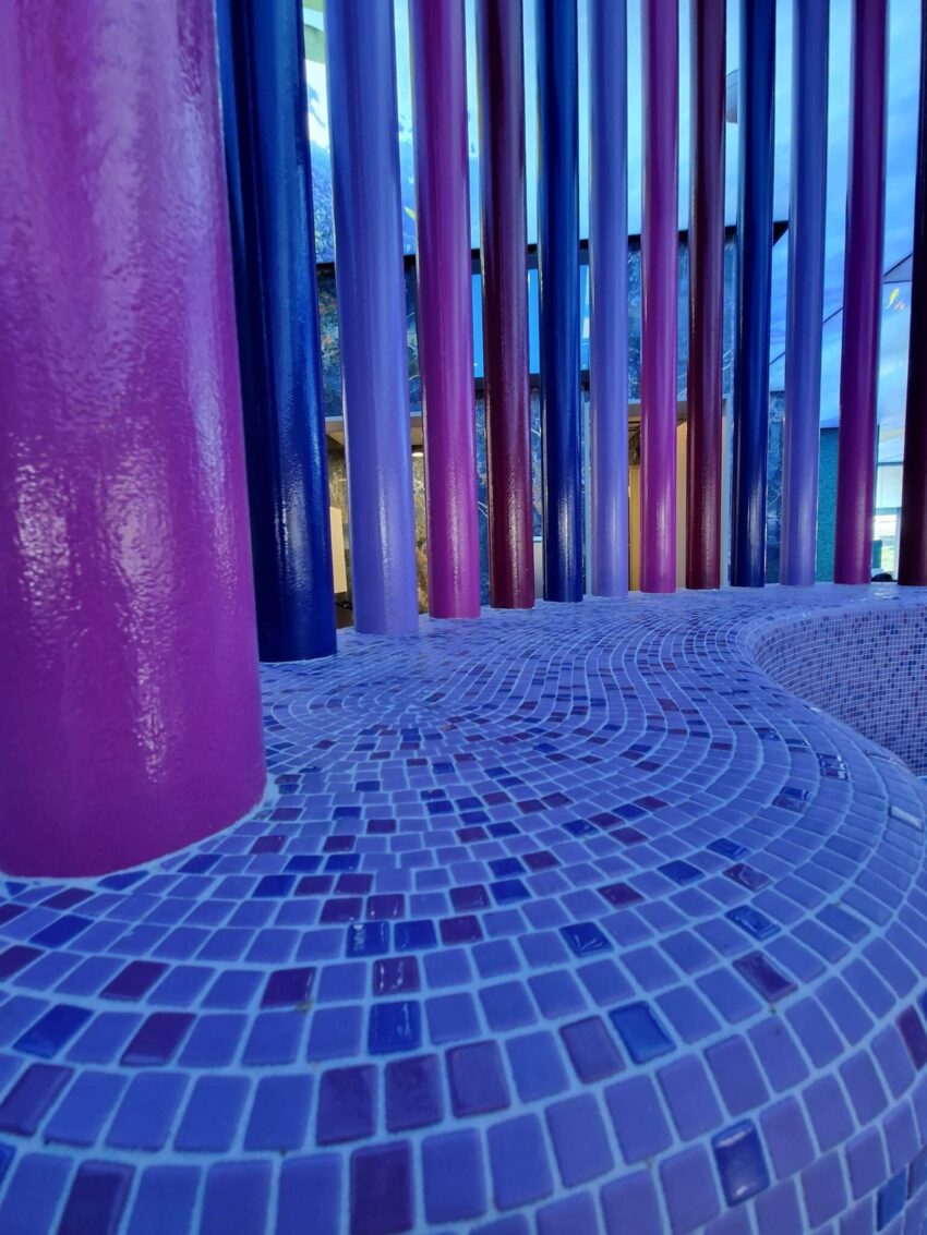 Nahaufnahme von bunten, mosaikverkleideten Säulen im Wellnessbereich.
