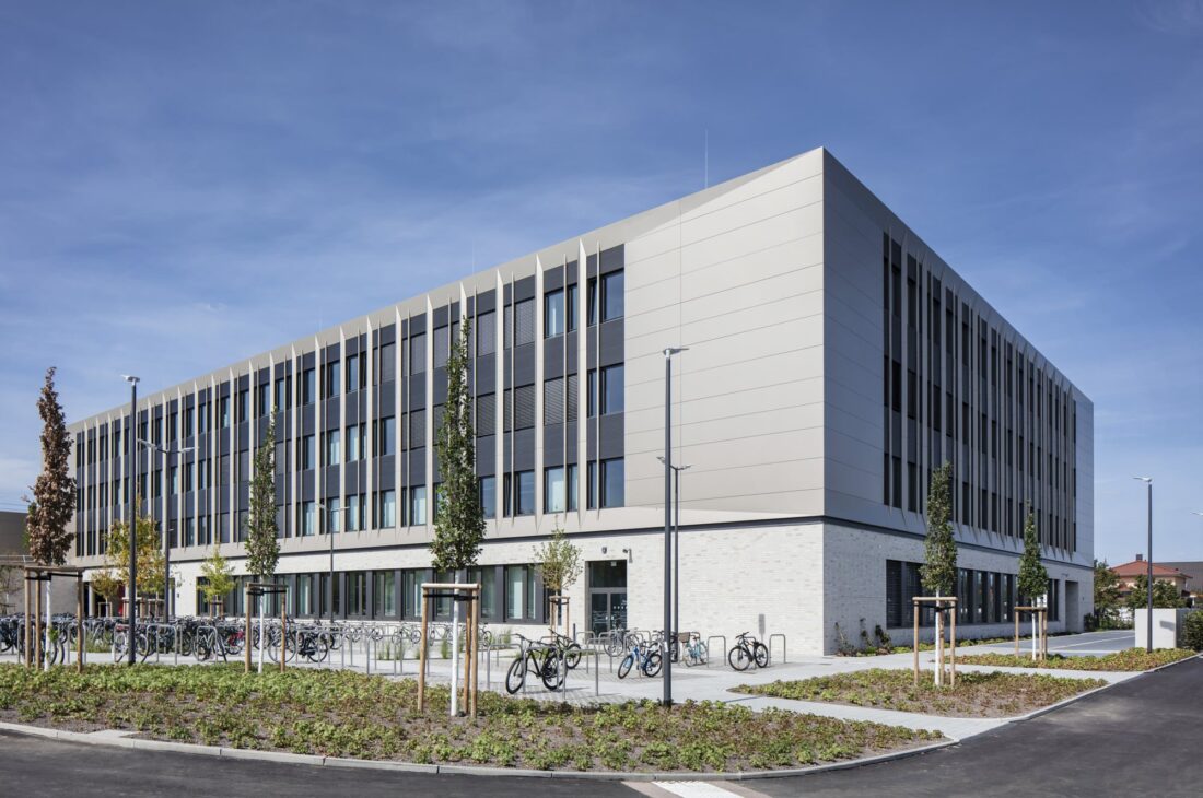Außenansicht des Gymnasiums Marie-Curie-Schule Leipzig mit moderner Fassade und Fahrradstellplätzen.