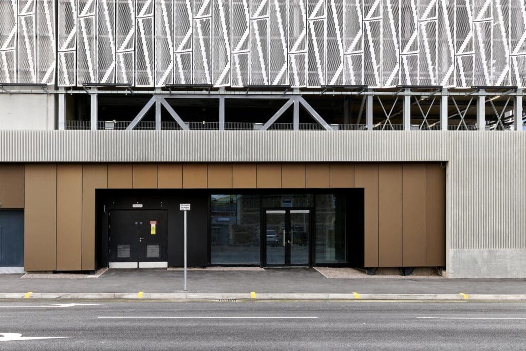 Als verbindendes, massives Element zwischen individuell gekanteten Aluminium-Lochblechen und Aluminium-Paneelen verleiht die Beton-Fassade Struktur und Klarheit.