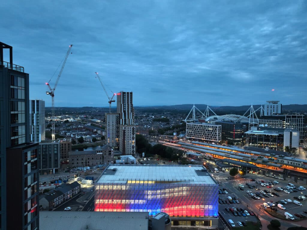 Nachtaufnahme des MSCP Central Quay in Cardiff mit farbig beleuchteter Fassade und Blick auf die Skyline der Stadt.