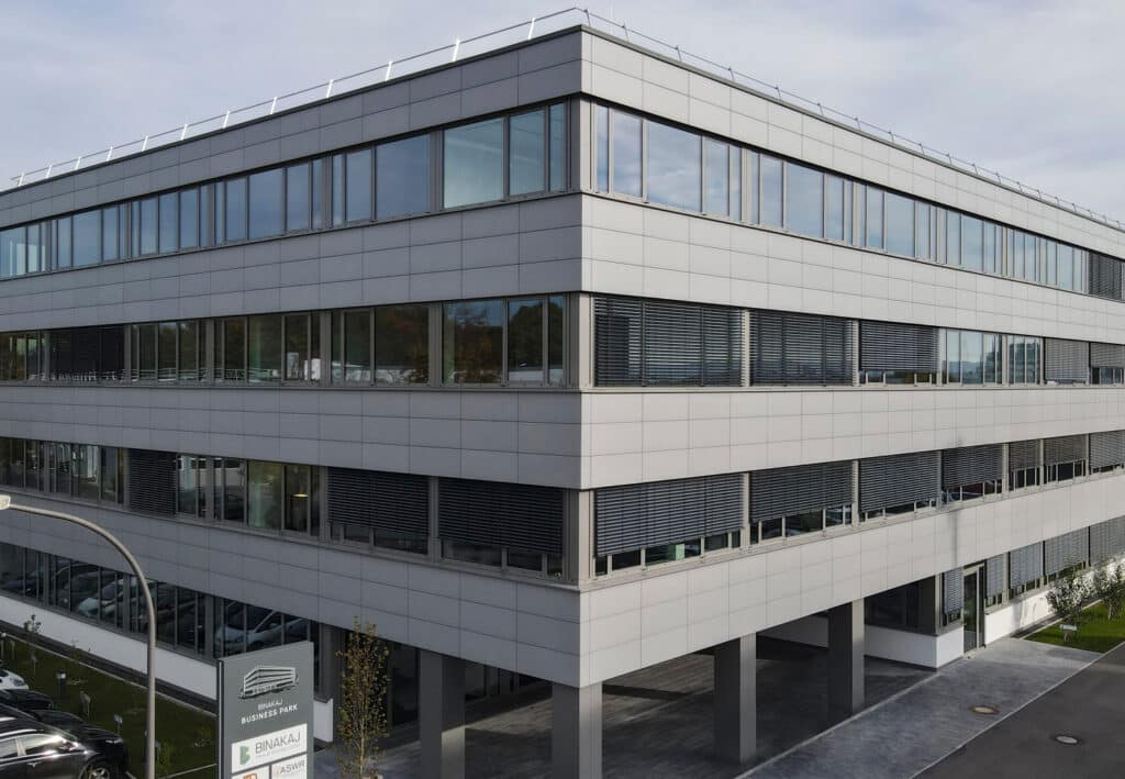Bürogebäude im Businesspark mit umlaufender Keramikfassade und Eckverglasung.