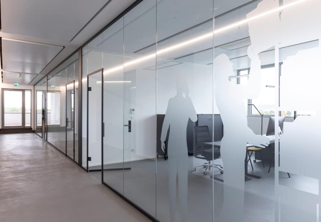 Helle Büroräume mit Glaswänden und Sichtschutzmotiven im Businesspark.