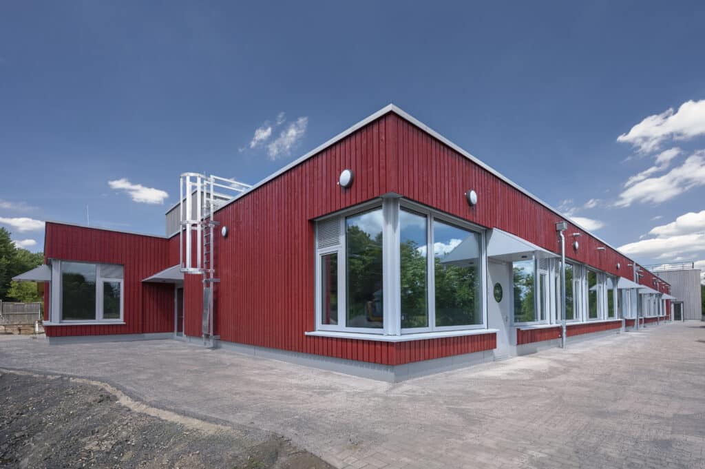 Neubau der Christoph-Schlingensief-Schule in Oberhausen mit roter Holzfassade und großen Fensterflächen.