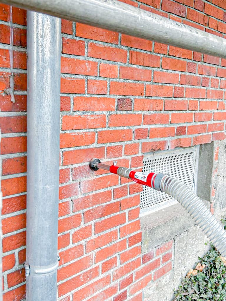 Fachgerechte Einblasdämmung mit flexiblem Schlauch in ein Ziegelmauerwerk.