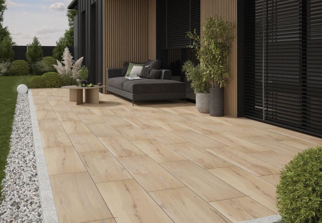 Terrasse mit keramischen Bodenplatten in Holzoptik, Lounge-Möbeln und moderner Fassadengestaltung mit Holzlamellen.