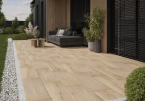 Terrasse mit keramischen Bodenplatten in Holzoptik, Lounge-Möbeln und moderner Fassadengestaltung mit Holzlamellen.
