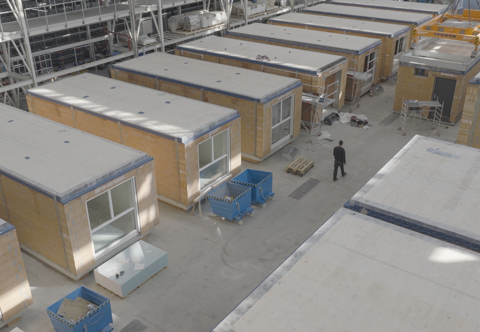 Mehrere vorgefertigte Ziegelmodule stehen strukturiert in einer Produktionshalle bereit, um weiter ausgebaut zu werden.