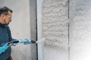 Handwerker beim maschinellen Auftragen von Dämmputz auf eine Fassade.