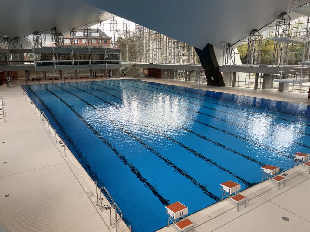 Innenansicht der Alsterschwimmhalle in Hamburg mit großem Schwimmbecken und Sprunganlagen.