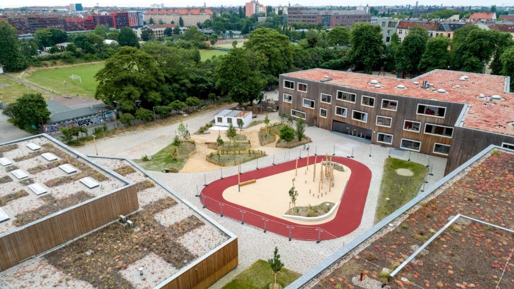 Luftaufnahme des Waldorfcampus Berlin mit begrünten Dachflächen, Spiellandschaft und umliegenden Grünflächen.