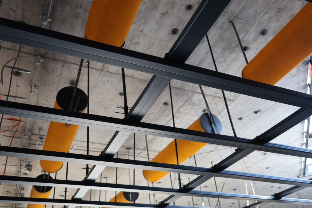 Lüftungsrohre und Metallkonstruktion unter Rohbetondecke