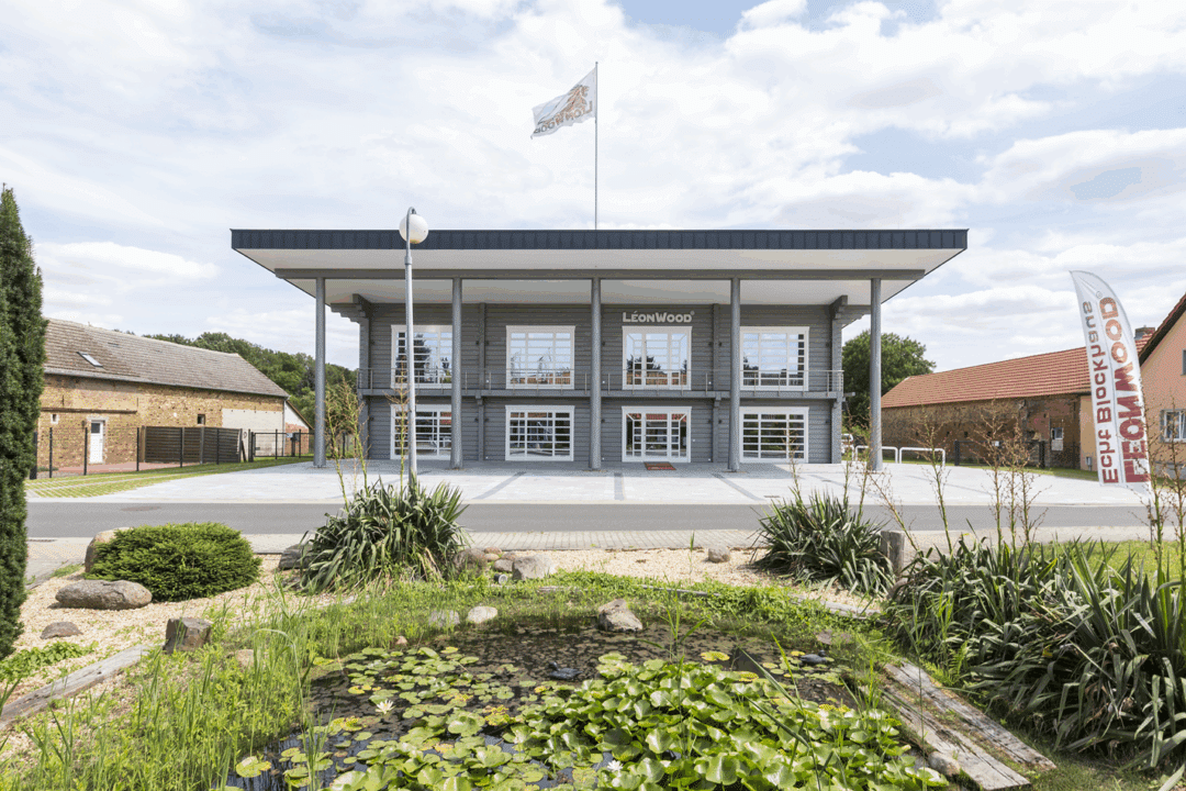 Moderne Holzbau-Architektur von LéonWood mit symmetrischer Fassade, Säulen und Außenanlage mit Teich