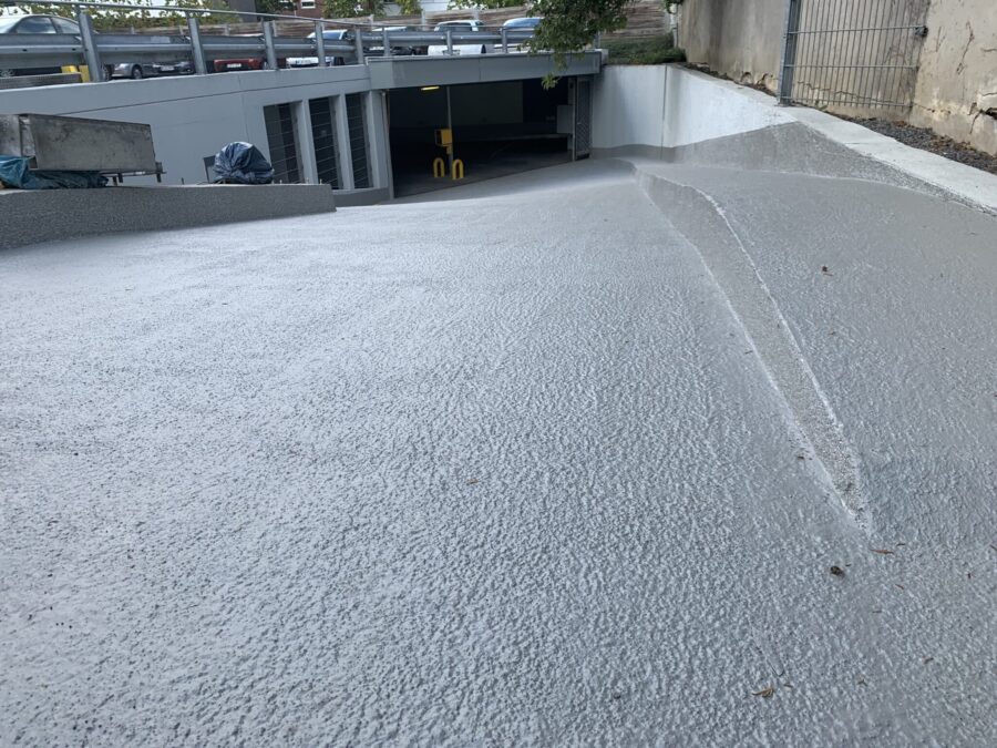 Neu sanierte Betonrampe einer Tiefgarage mit gleichmäßig strukturierter Beschichtung.