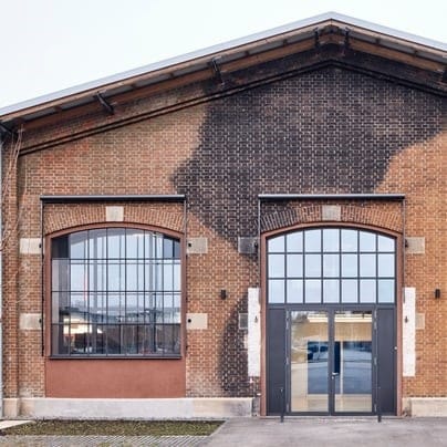 Fassade eines sanierten Backsteingebäudes mit großen Fenstern und Glaseingang
