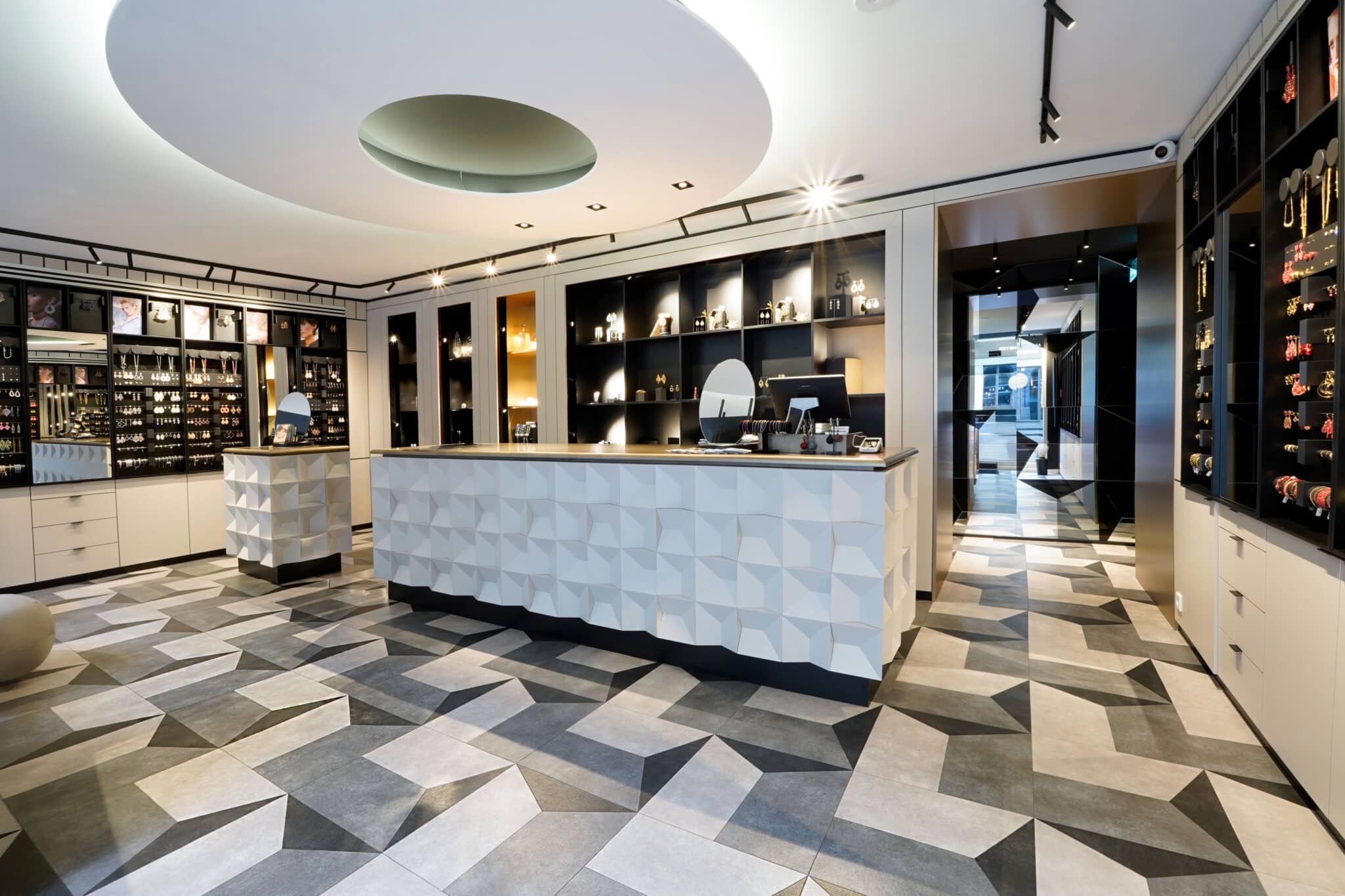 Innenraum eines hochwertigen Schmuckgeschäfts mit geometrischem Designboden aus großformatigen Fliesen, modernem Tresen und beleuchteten Präsentationsflächen.