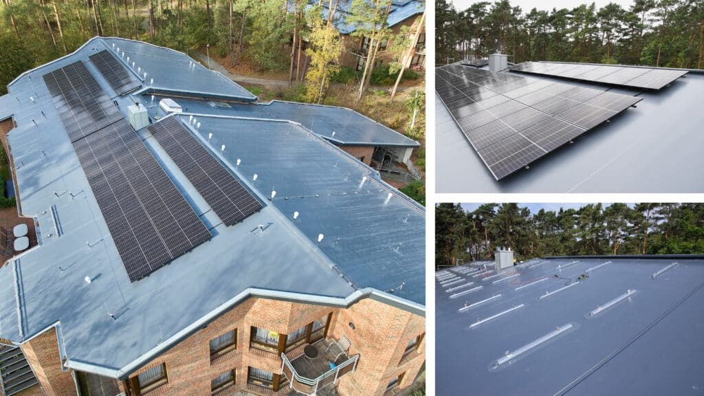 Dachanlage mit Photovoltaikmodulen auf mehrteiligem Flachdach eines Gebäudes, umgeben von Bäumen.