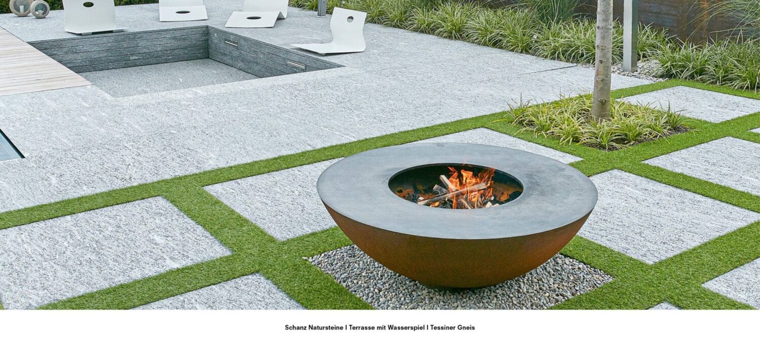 Moderne Terrasse aus Tessiner Gneis mit eingelassenem Wasserspiel, Feuerstelle und Sitzbereich.