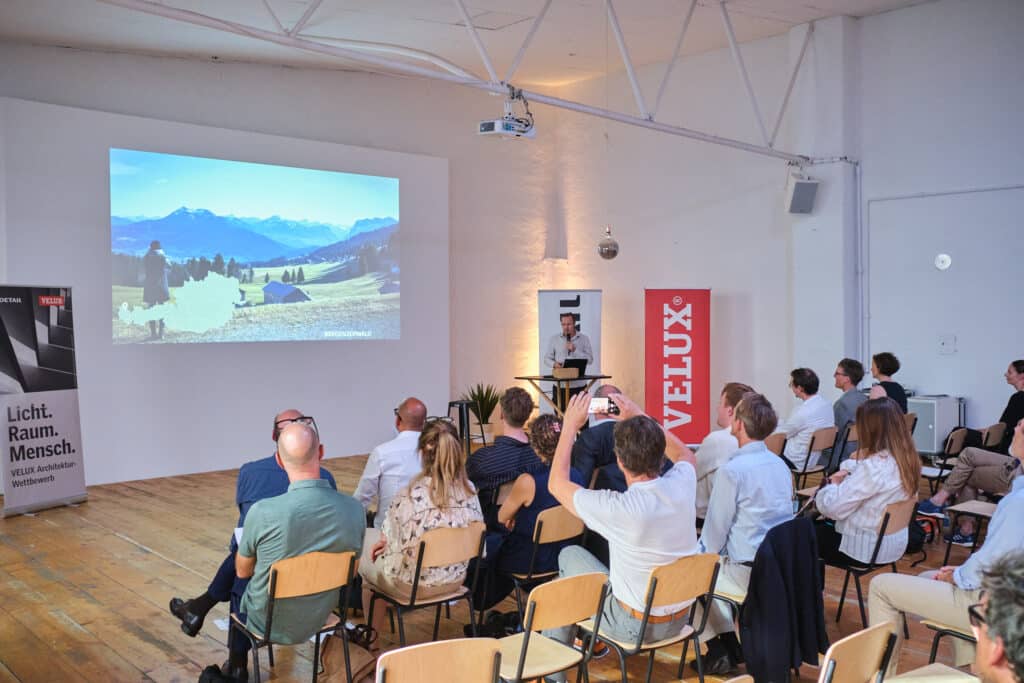Vortragender zeigt Berglandschaft auf Leinwand bei VELUX Architekturwettbewerb.