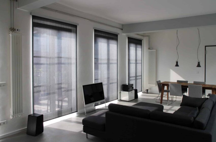 Helles Wohnzimmer mit großen bodentiefen Fenstern und halbtransparenten Low-E-Rollos zum Sonnenschutz.