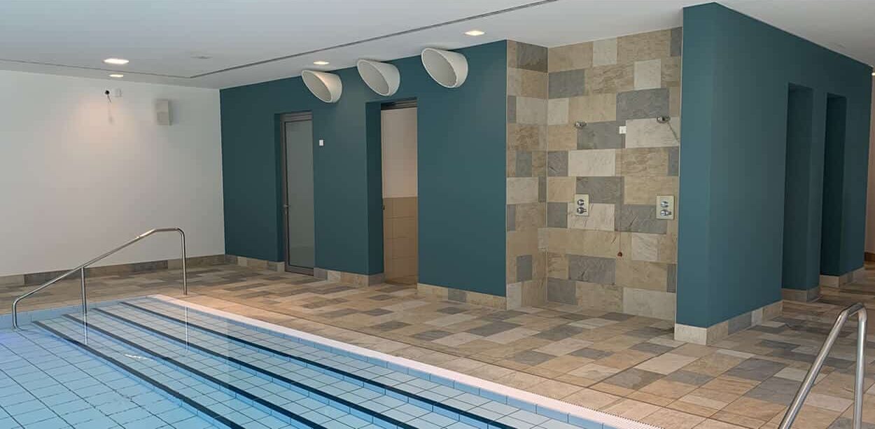 Moderne Schwimmbadanlage mit großformatigen Wandfliesen und Bodenbelag, Beispiel für fachgerechte Abdichtung und Fliesenverlegung.