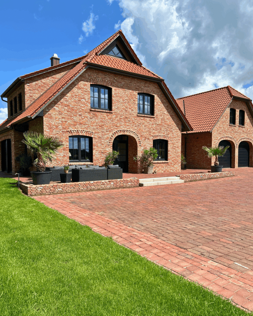 Ansicht des fertiggestellten Einfamilienhauses aus rotem Klinker mit Ziegeldach und Garagenanbau.