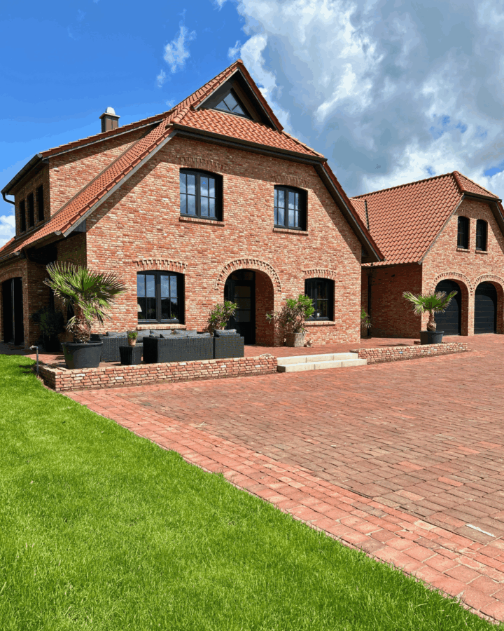 Ansicht des fertiggestellten Einfamilienhauses aus rotem Klinker mit Ziegeldach und Garagenanbau.