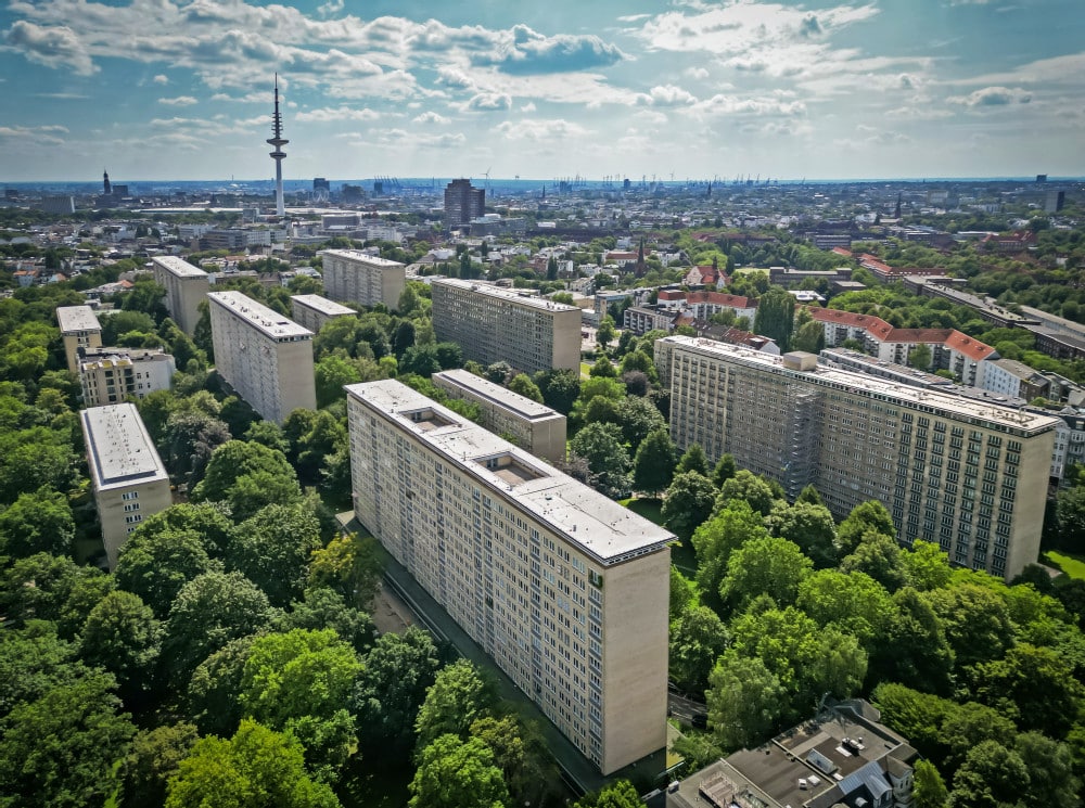 Luftaufnahme der Grindelhäuser in Hamburg mit umliegenden Grünflächen und Fernsehturm im Hintergrund.