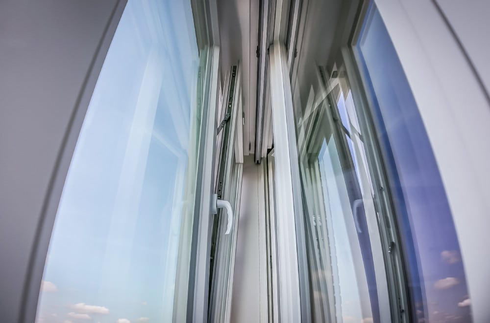 Detailaufnahme eines modernen Kastenfensters mit Automatikbeschlägen und Spiegelung im Glas.