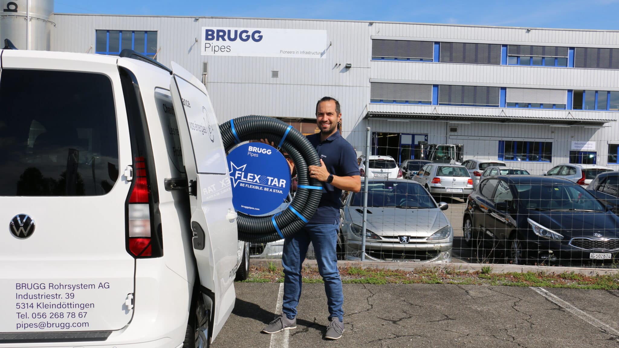 Mitarbeiter vor BRUGG Pipes Gebäude mit FLEXSTAR Rohrsystem.