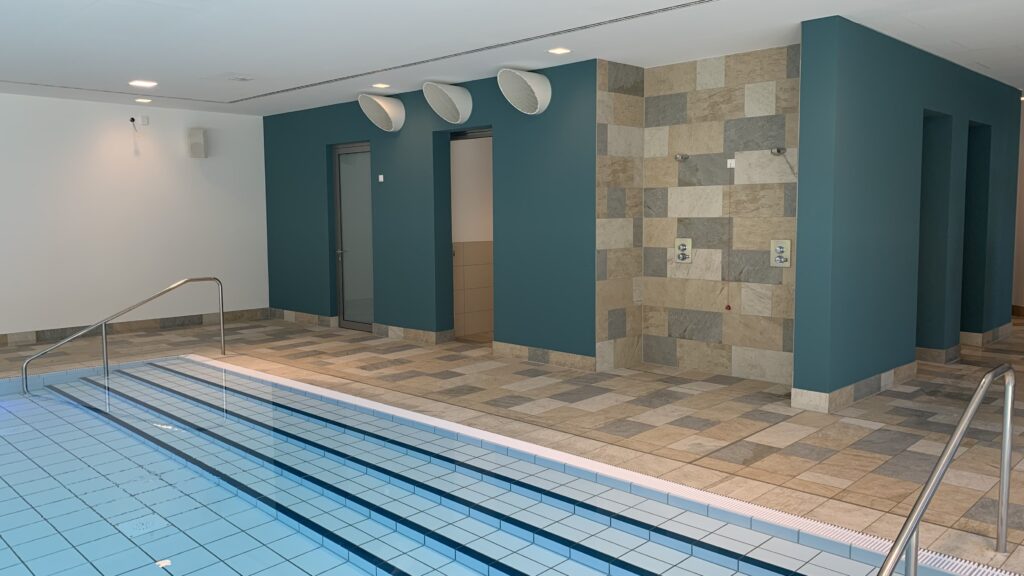 Moderne Schwimmbadanlage mit großformatigen Wandfliesen und Bodenbelag, Beispiel für fachgerechte Abdichtung und Fliesenverlegung.