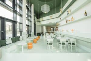 Innenansicht eines modernen Restaurants mit grüner und weißer Wandgestaltung sowie orangefarbenen Hockern