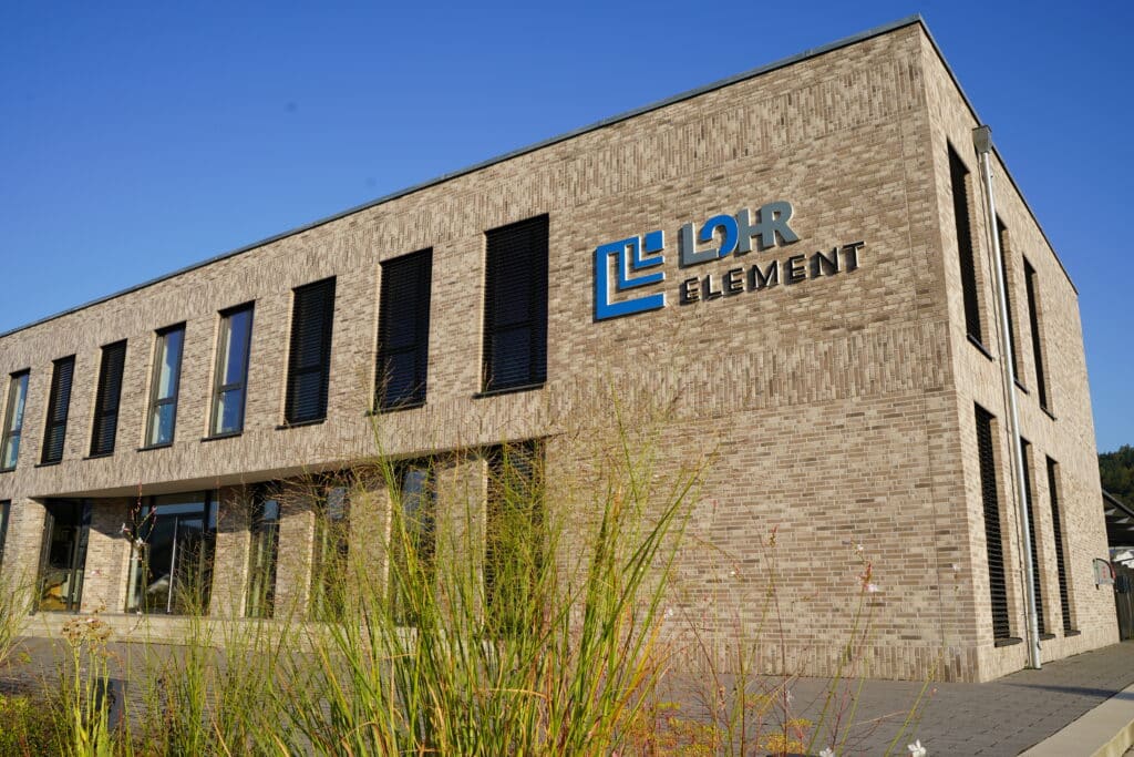 Vorderansicht des LohrElement-Firmengebäudes mit moderner Backsteinfassade, großen Fensterflächen und dem Unternehmenslogo an der Außenwand.