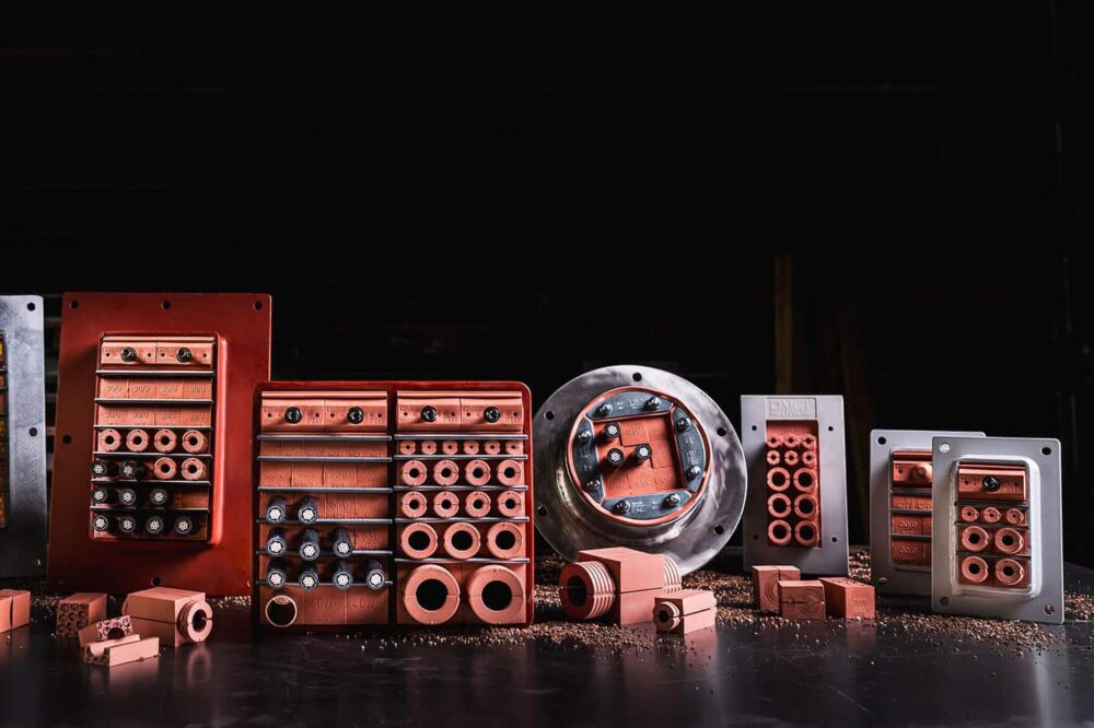 Verschiedene MCT Brattberg Modulabschottungen in rechteckigen und runden Rahmen, ausgestattet mit Kabeln und Dichtmodulen, für sicheren Brand-, Gas- und Wasserschutz.