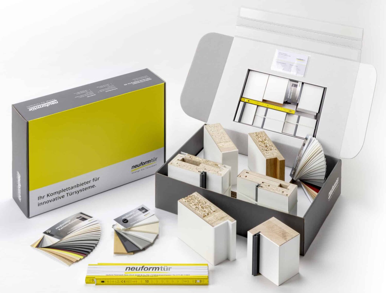 Geöffnete neuformtür Musterbox mit verschiedenen Türprofil-Modellen, Material- und Farbmustern sowie einem Zollstock – präsentiert als Komplettset für innovative Türsysteme.