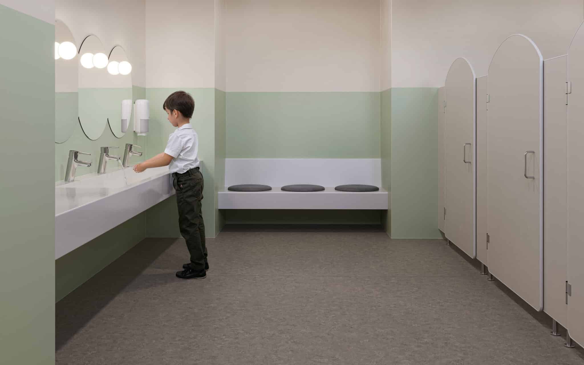 Kindgerechter Waschraum mit rutschfestem, pflegeleichtem Boden, pastellfarbenen Wänden und modernen Waschtischen.