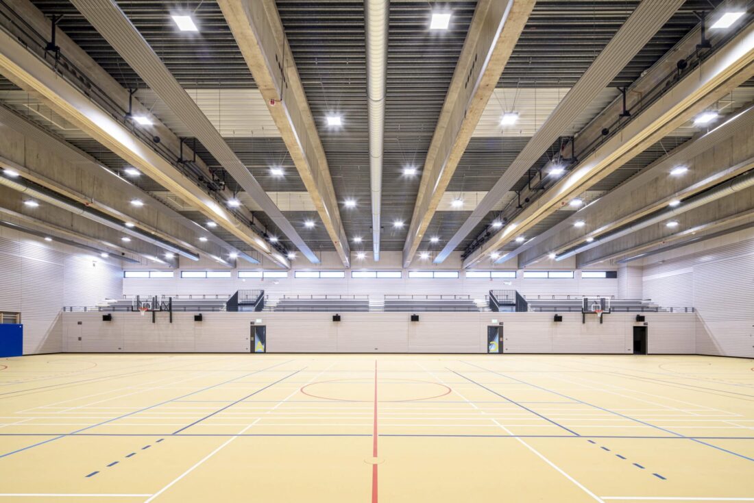 Produktionshalle mit rotem Regalsystem und hellen Deckenstrahlplatten für effiziente Wärmeverteilung.