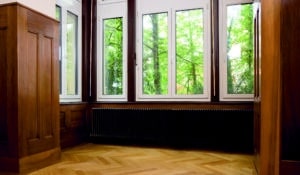 Stilvoll renovierter Altbau mit dunklem Zehnder Charleston Heizkörper vor großen Fenstern.