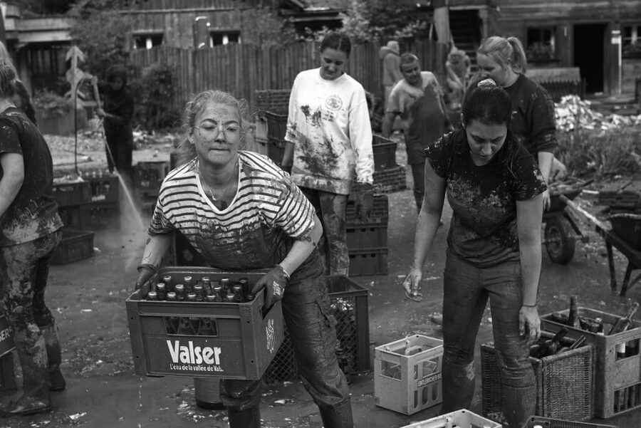 Menschen reinigen verschmutzte Getränkekisten nach Hochwasserereignis.