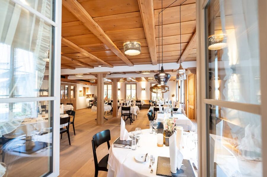 Modern eingerichtetes Restaurant mit Holzelementen und gedeckten Tischen.