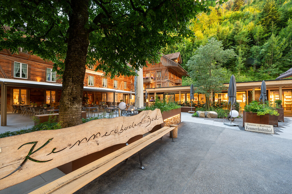 Außenansicht des Kemmeriboden-Bads mit Terrasse und Baum im Vordergrund.