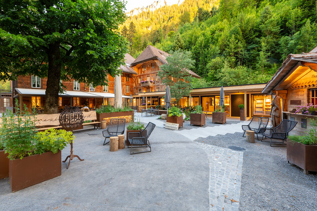 Innenhof des Kemmeriboden-Bads mit Sitzplätzen, Pflanzen und Bergkulisse.