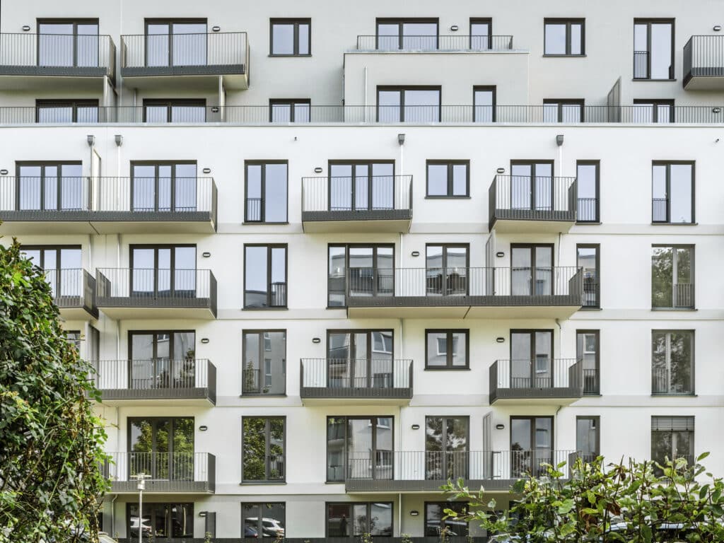 Frontale Ansicht der Wohnfassade mit übereinander angeordneten Balkonen und großflächigen Fensteröffnungen.