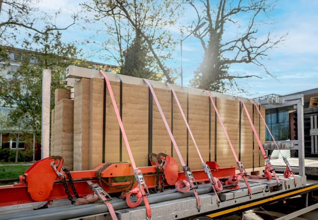 Vorfertigte Stampflehmwand-Elemente von Leipfinger-Bader, gesichert mit Spanngurten auf einem LKW für den Transport zur Baustelle.